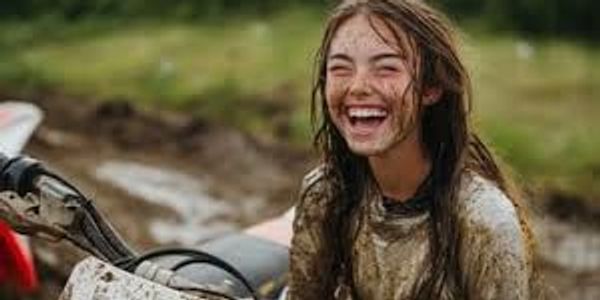 Happy girl covered in mud after riding a dirt bike.