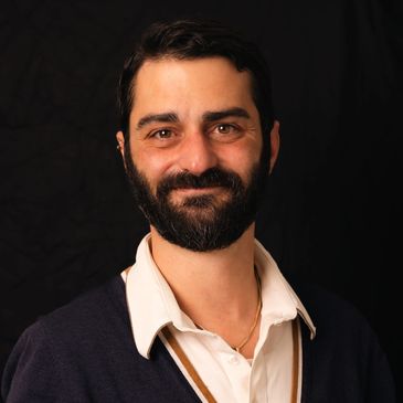 Portrait of a smiling man with beard and dark hair.