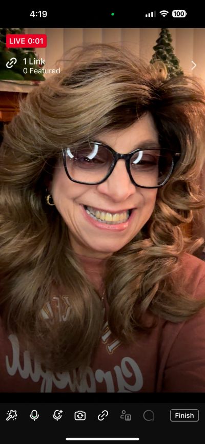 Woman with glasses smiling in a live video.