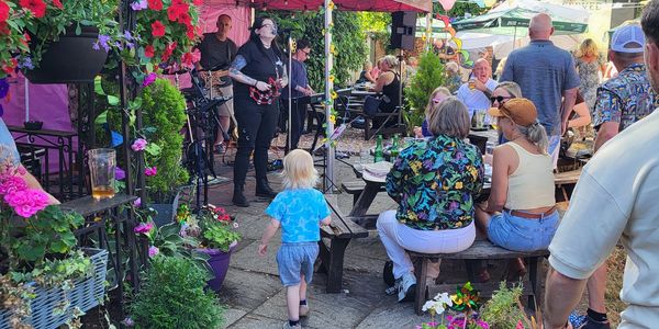 Outdoor gathering with live music and people enjoying a sunny day.