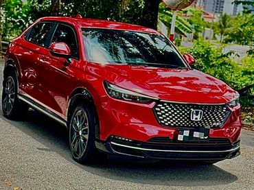 Red Honda SUV parked on a street with greenery around.