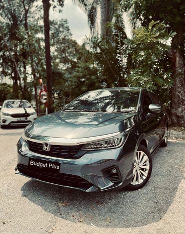 Sleek gray Honda sedan parked on a tree-lined street with a "Budget Plus" license plate.