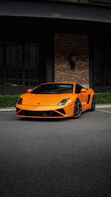 Bright orange Lamborghini sports car parked in front of a building.