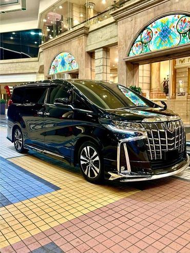 Black luxury van parked in a stylish, tiled lobby with stained glass windows.