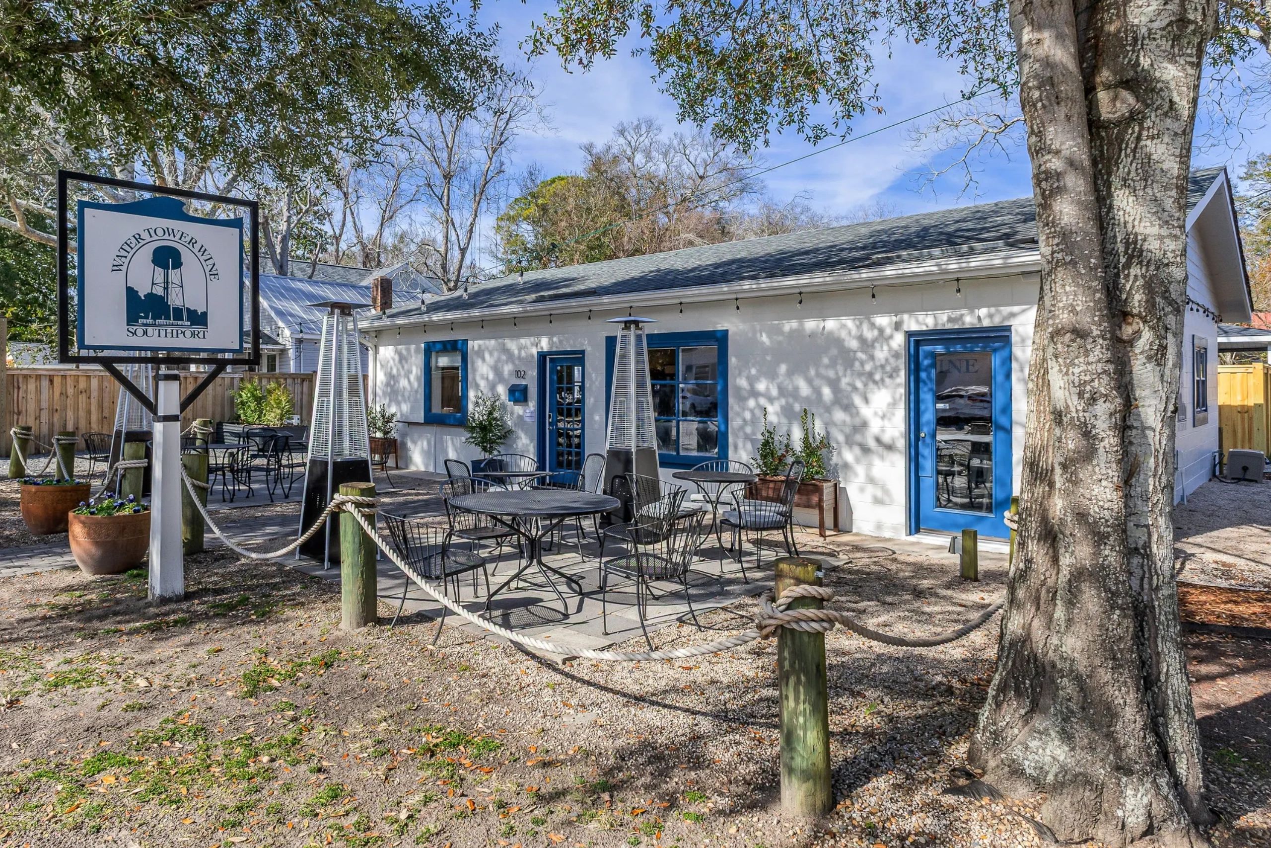 Outdoor seating area at Water Tower Wine in Southport with blue-trimmed windows.