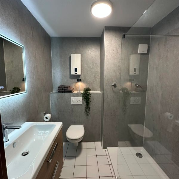 Modernes Badezimmer mit grauen Wänden und Glasdusche.