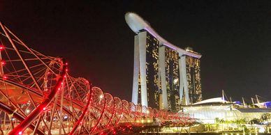 Singapore city lit up at night with the bridge in the foreground and Marina Bay Sands hotel.