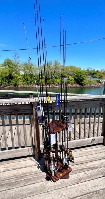Fishing rods standing on a wooden deck by the water.