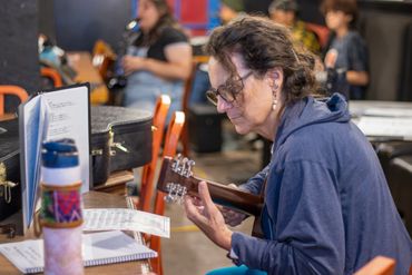 Woman focused on playing guitar during a music practice session.