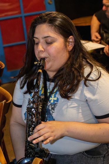 Person playing saxophone indoors with eyes closed.