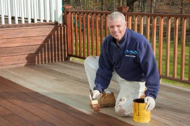 A contractor applying stain to a new back yard porch.