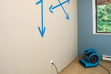 Residential air mover blower fan in a room drying out water damage.