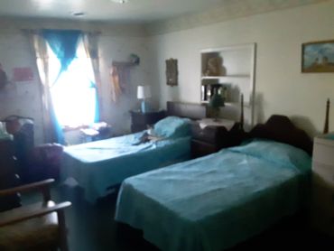 A dimly lit bedroom with two single beds covered in blue bedspreads.