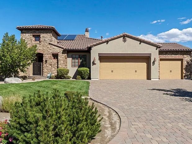 Modern house with stone and stucco exterior and solar panels.