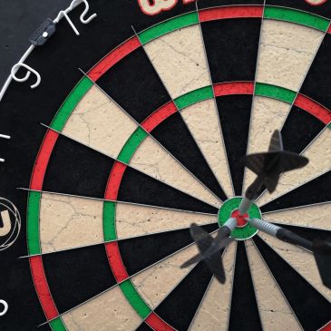 Three darts hitting the bullseye on a dartboard.