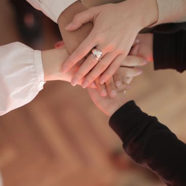 Four hands stacked together in unity.