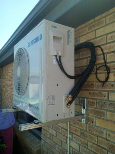 Samsung outdoor air conditioner unit mounted on brick wall.
