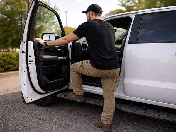 Construction worker in black shirt getting in vehicle and clipboard at a gravel site.