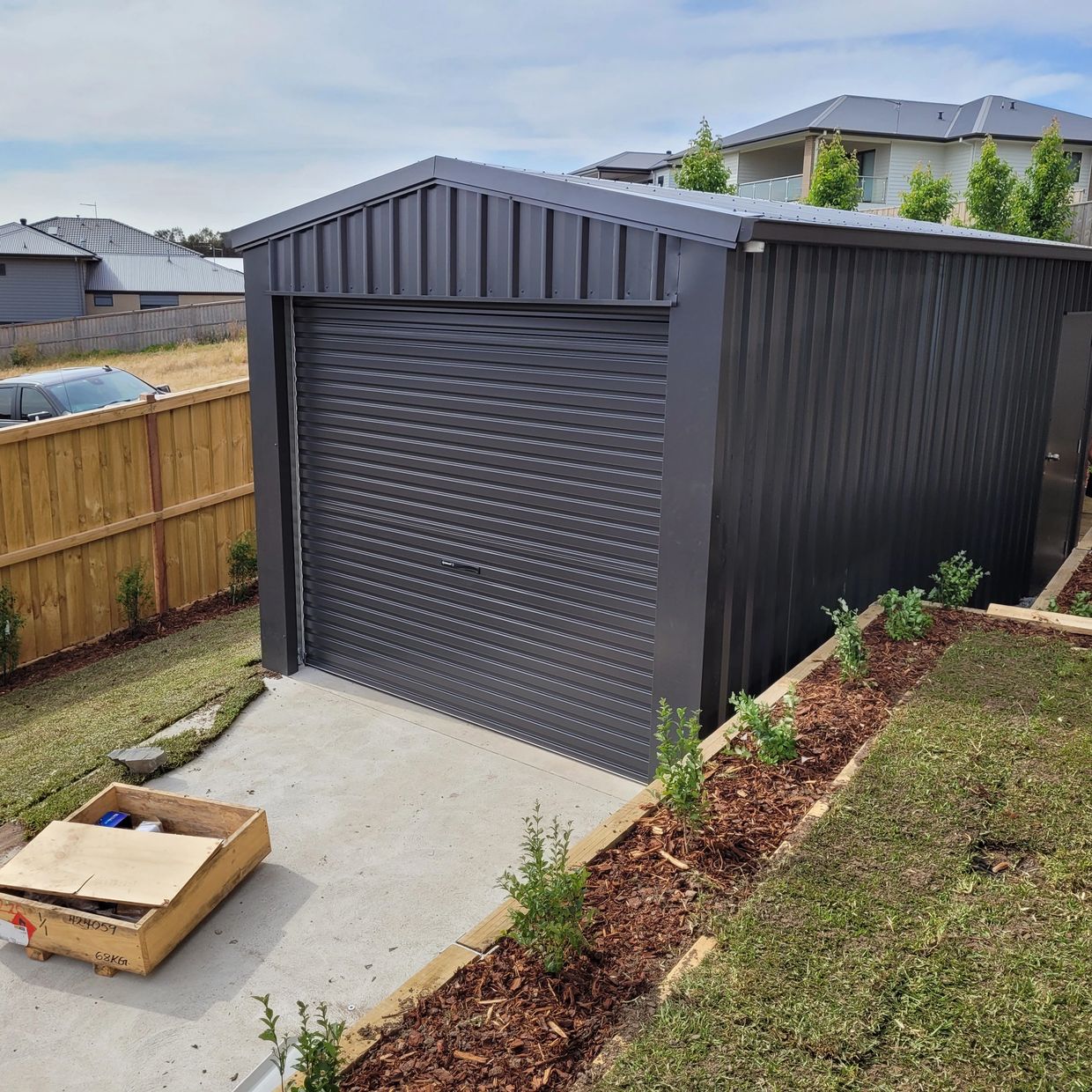 Small one car shed with roller door and personal access door. Made with dark grey color bond.