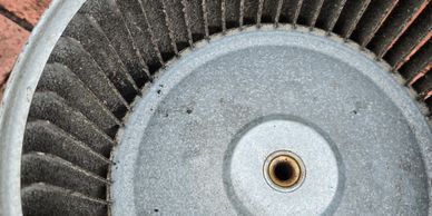 Close-up of a circular metal fan or blower wheel with radial blades.