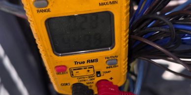 Yellow digital multimeter measuring electrical values.