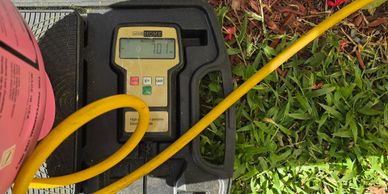 Digital gauge reading 70.7 connected to yellow hose outdoors.