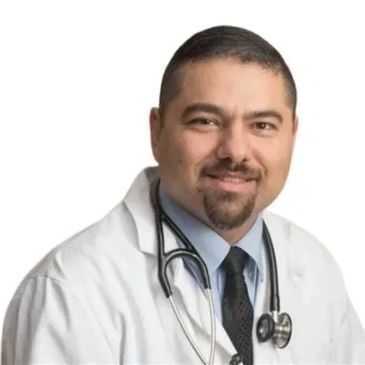 Smiling male doctor wearing a white coat and stethoscope.