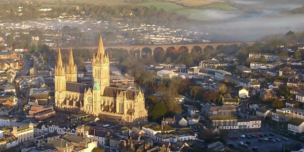 A historic cathedral with three spires in a small town at sunrise.
