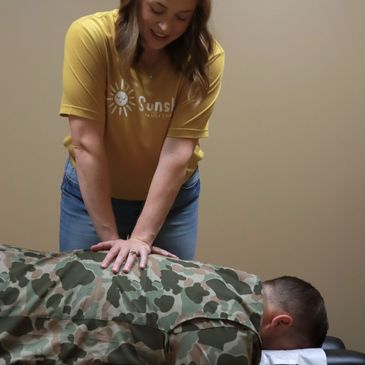 Dr. Katelyn Wilson giving a chiropractic adjustment to a man in a camo shirt