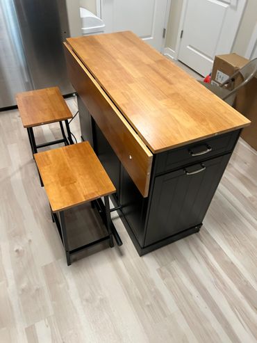 Compact kitchen island with wooden top and two stools.