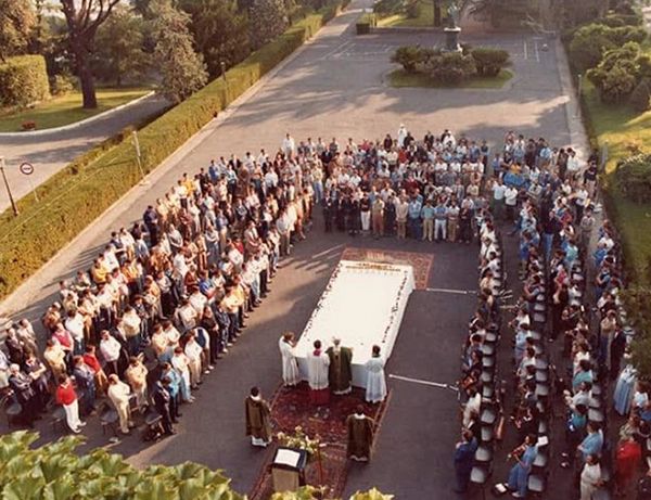 Large outdoor religious gathering with people around altar.