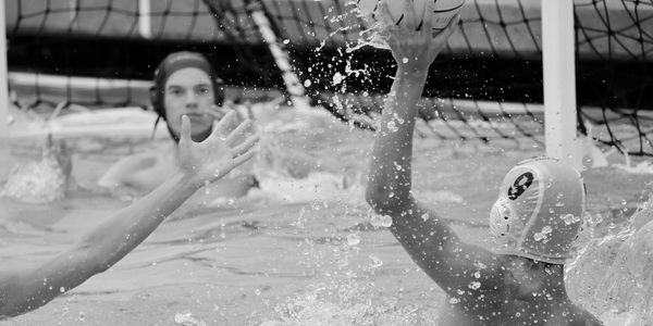 Boys' water polo scoring a goal with a splash.