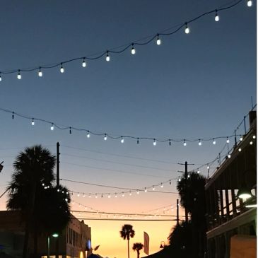 String lights hanging over a street at sunset.