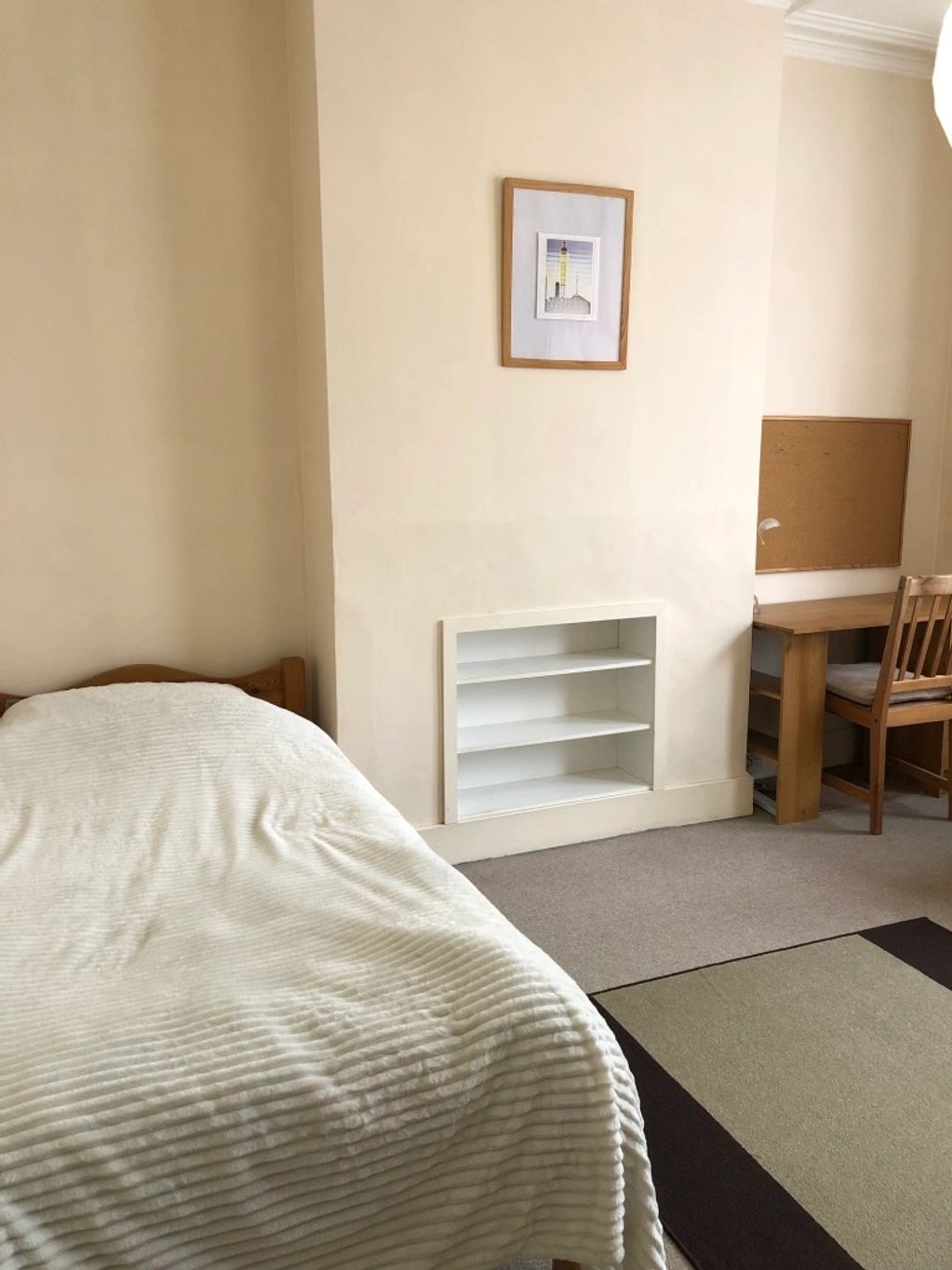 Minimalist bedroom with a bed, built-in shelves, desk, and chair.