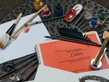 Calligraphy tools and ink on a decorative metal table with a calligraphy book.