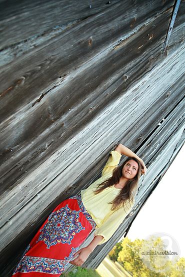 High school girl leaning on rustic old barn
