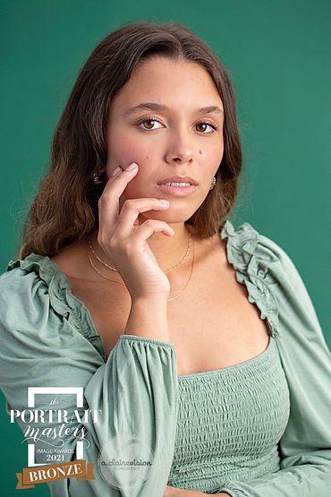 Bronze award winning portrait of high school girl on teal backdrop