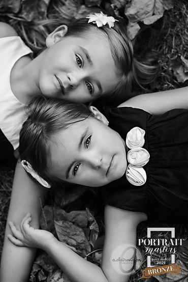 Bronze medal winning portrait in black and white of two sister lying in the leaves