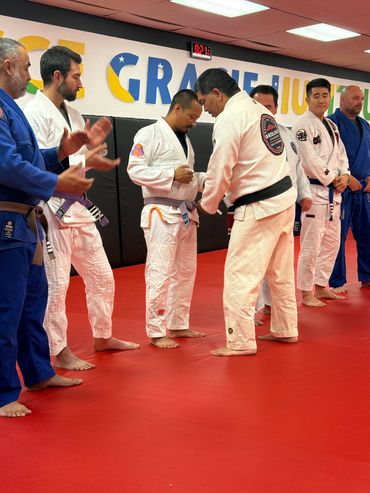Black Belt Instructor awarding progress stripe during Gracie Jiu Jitsu, Brazilian Jiu Jitsu promotio