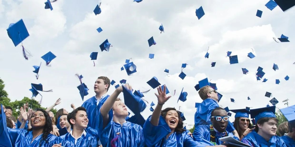 A group of recent college graduates throwing their graduation hats into the air.