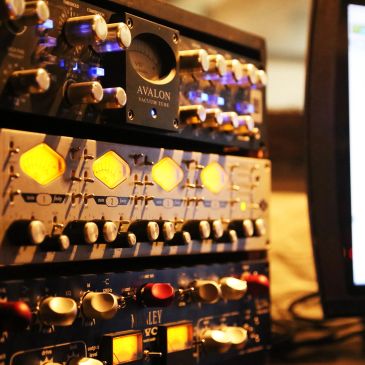 Close-up of professional audio equipment with glowing knobs and meters.