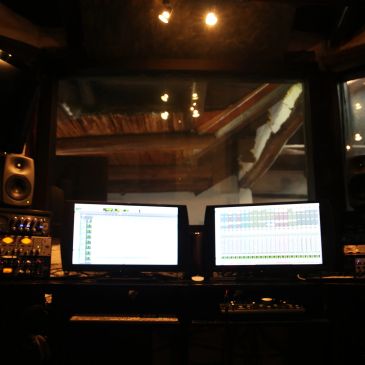 Recording studio setup with dual monitors and speakers.