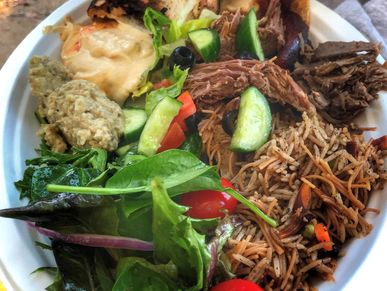 Delicious Mediterranean dinner featuring roast lamb, green salad roasted vegetables, and more
