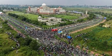 Aerial view of a large crowd gathered on roads near a grand building.