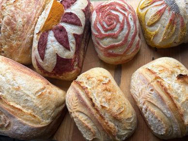 Assortment of artisan breads with decorative crust patterns on a wooden surface.