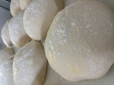 Close-up of dough balls dusted with flour, ready for baking.