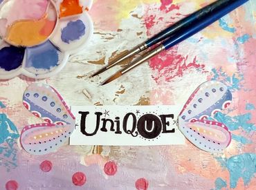 Artistic setup with paintbrushes and the word 'Unique' on a colorful palette.