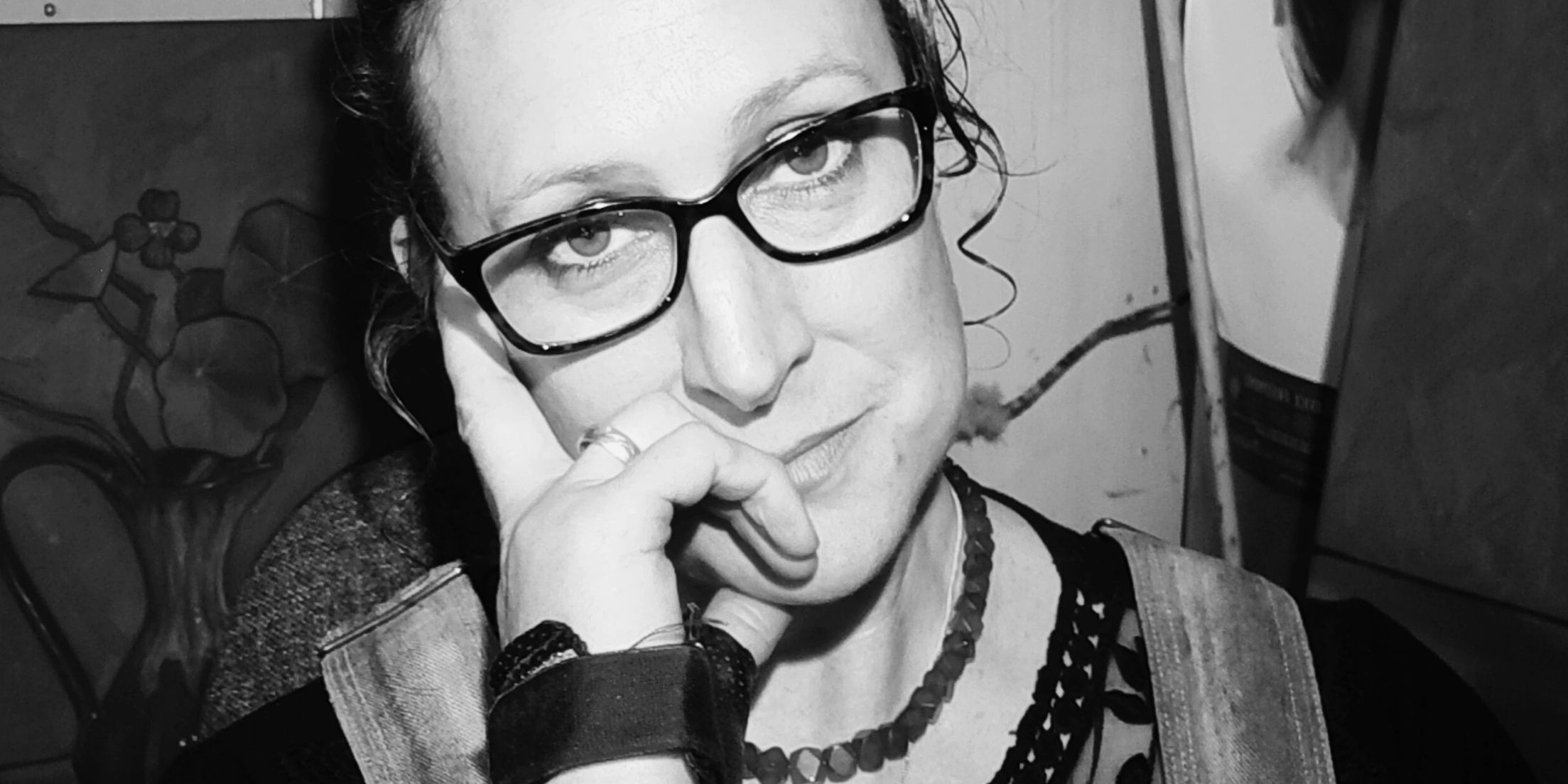 A photo of the artist Jonette Murray, smiling, wearing glasses.
