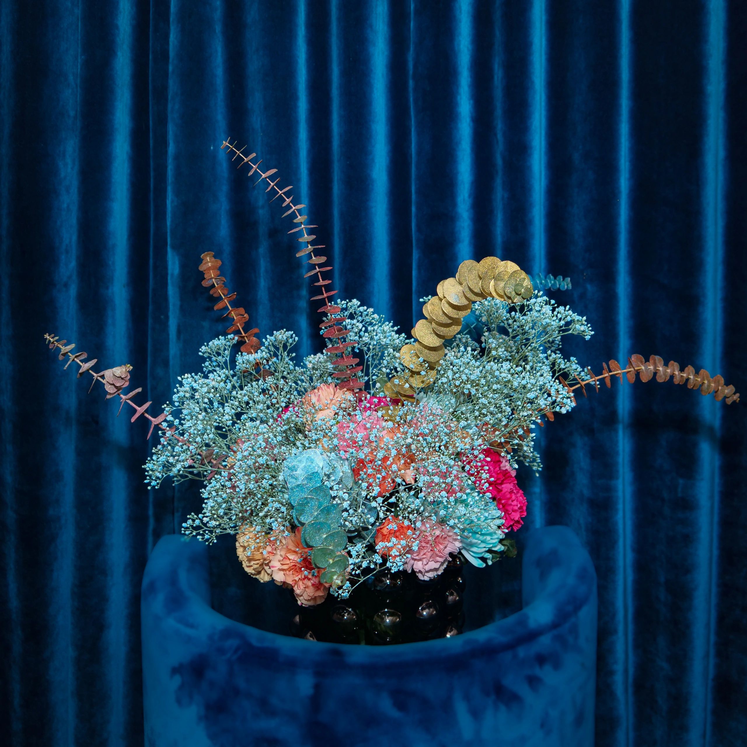 a baby blue bouquet in front of blue velvet curtains