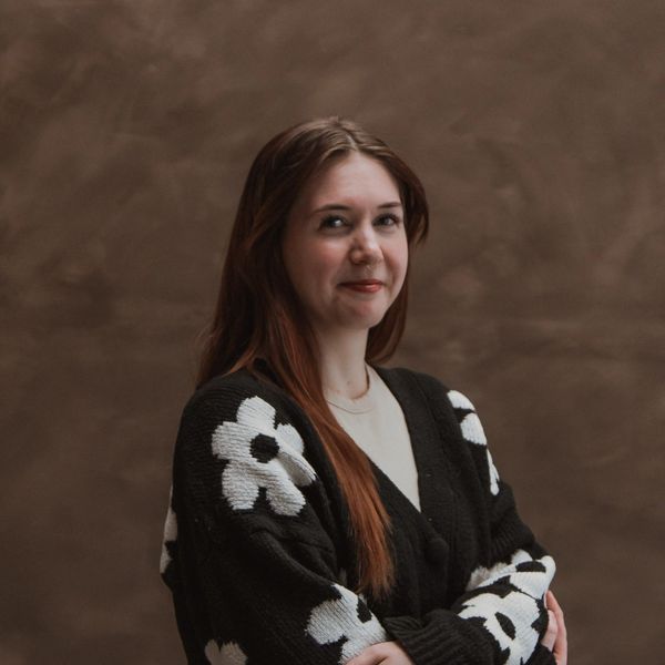Young woman with long hair wearing a black sweater with white flowers.